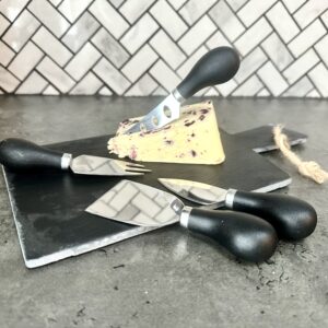 slate cheese board with knives and a block of cheese