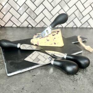 slate cheese board with knives and a block of cheese