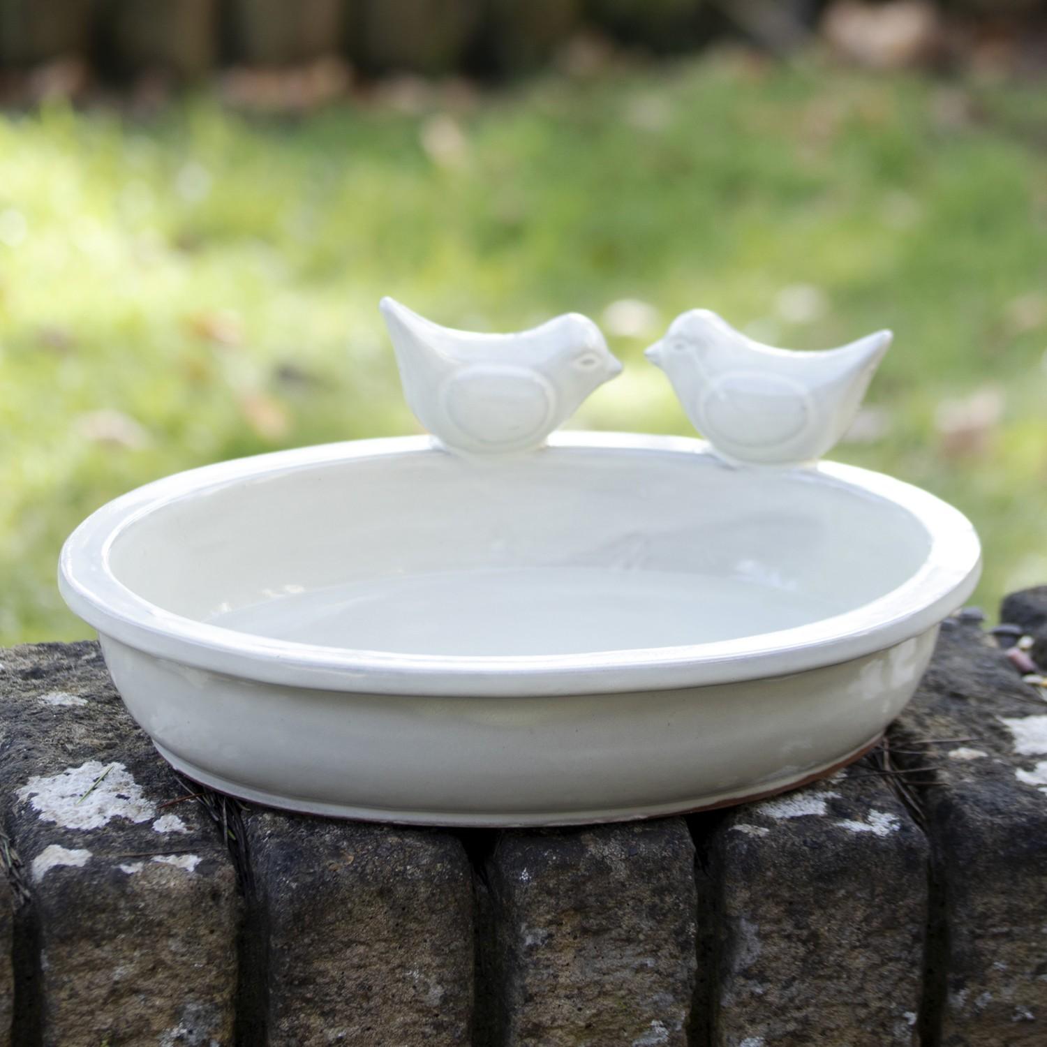 Ceramic bird bath and feeder with two decorative birds perched on the rim